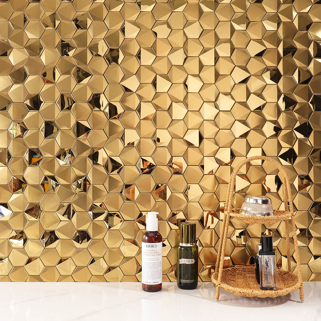 Gold hexagon mosaic backsplash featuring luxury skincare brand bottles.