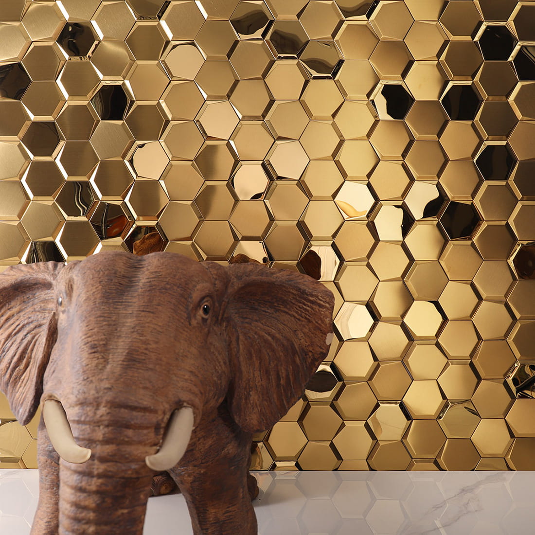 Gold hexagon tile wall installation next to a brown decorative elephant sculpture.