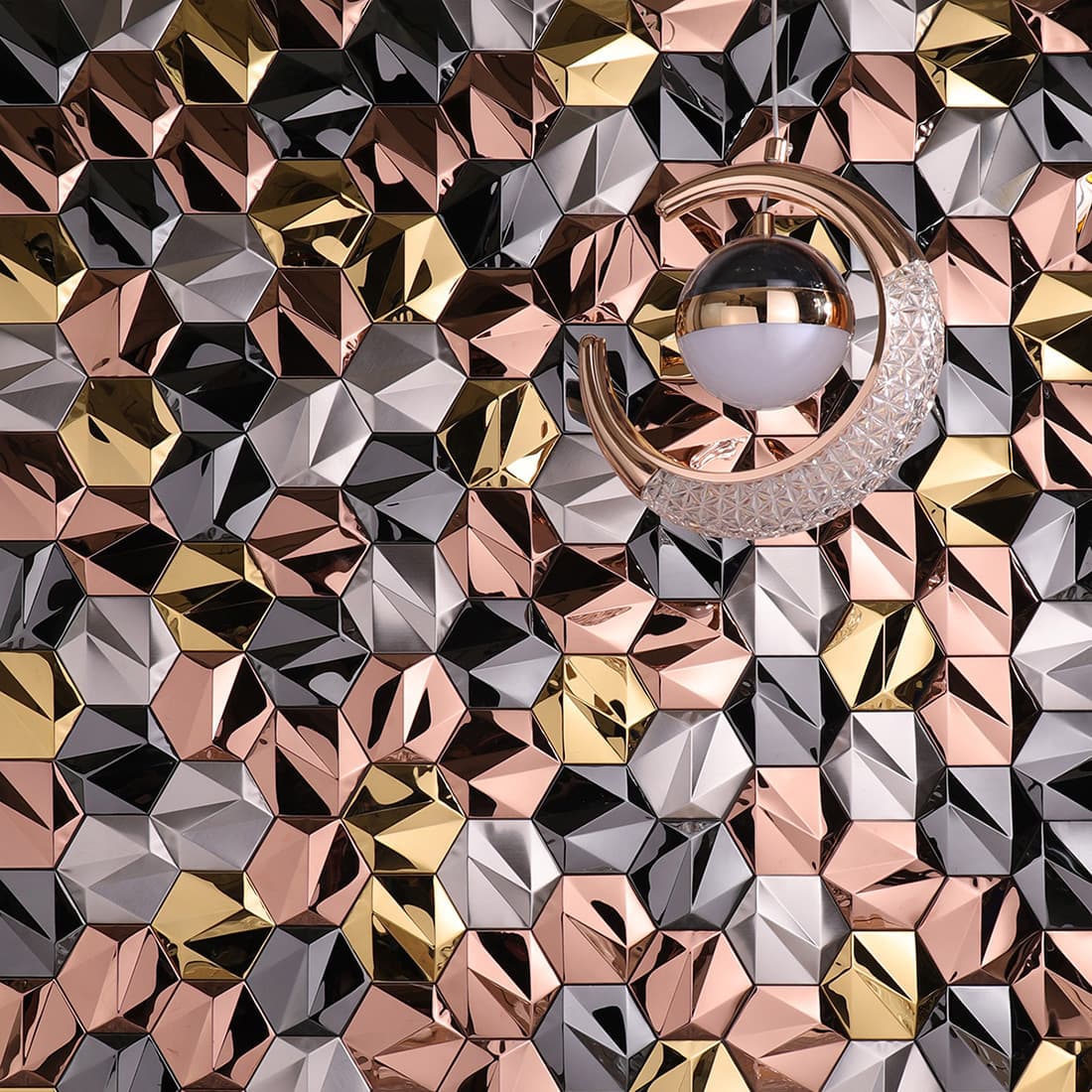 A full accent wall of 3D metallic tiles paired with a modern crescent pendant light
