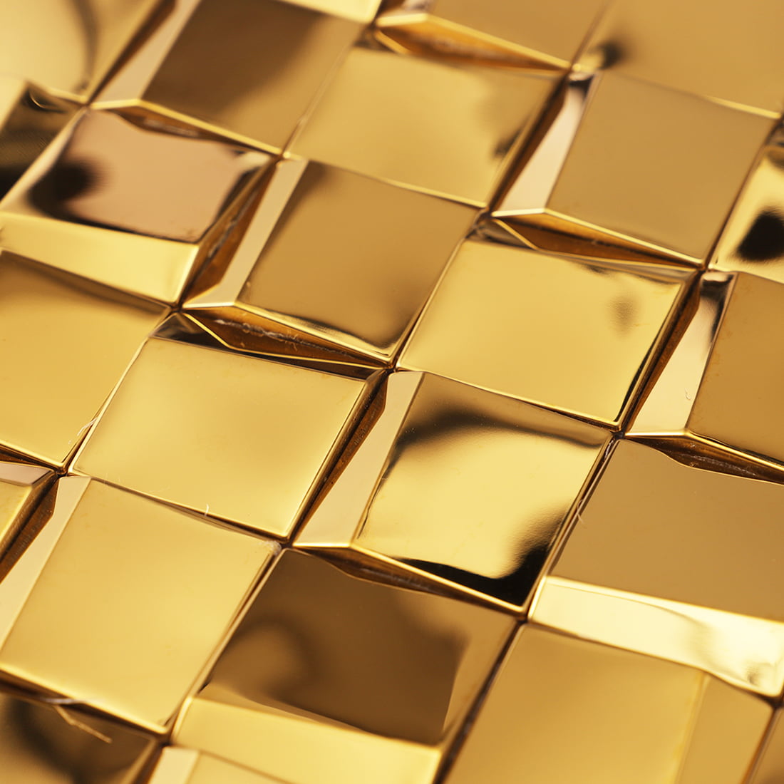 Macro view of a gold 3D geometric mosaic tile surface highlighting the 3D effect