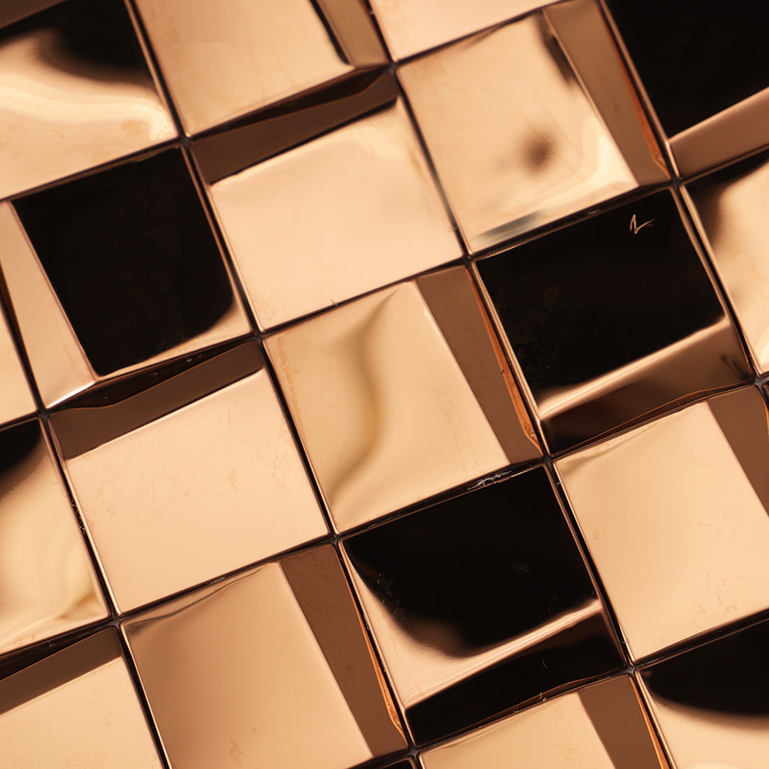 Macro view of a rose gold 3D geometric mosaic tile surface and reflections.