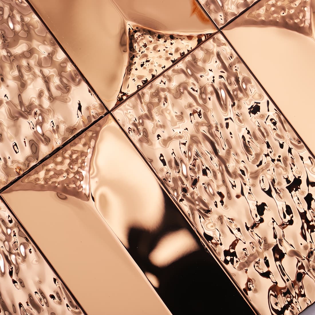 Macro detail of a rose gold metal tile surface with smooth mirrored and textured panels.