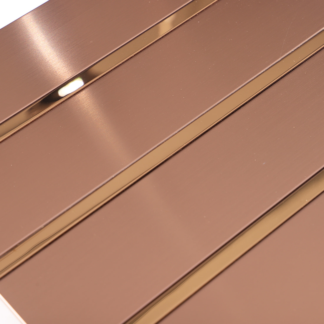 Macro shot of rose gold brushed metal mosaic tile surface with gold strips