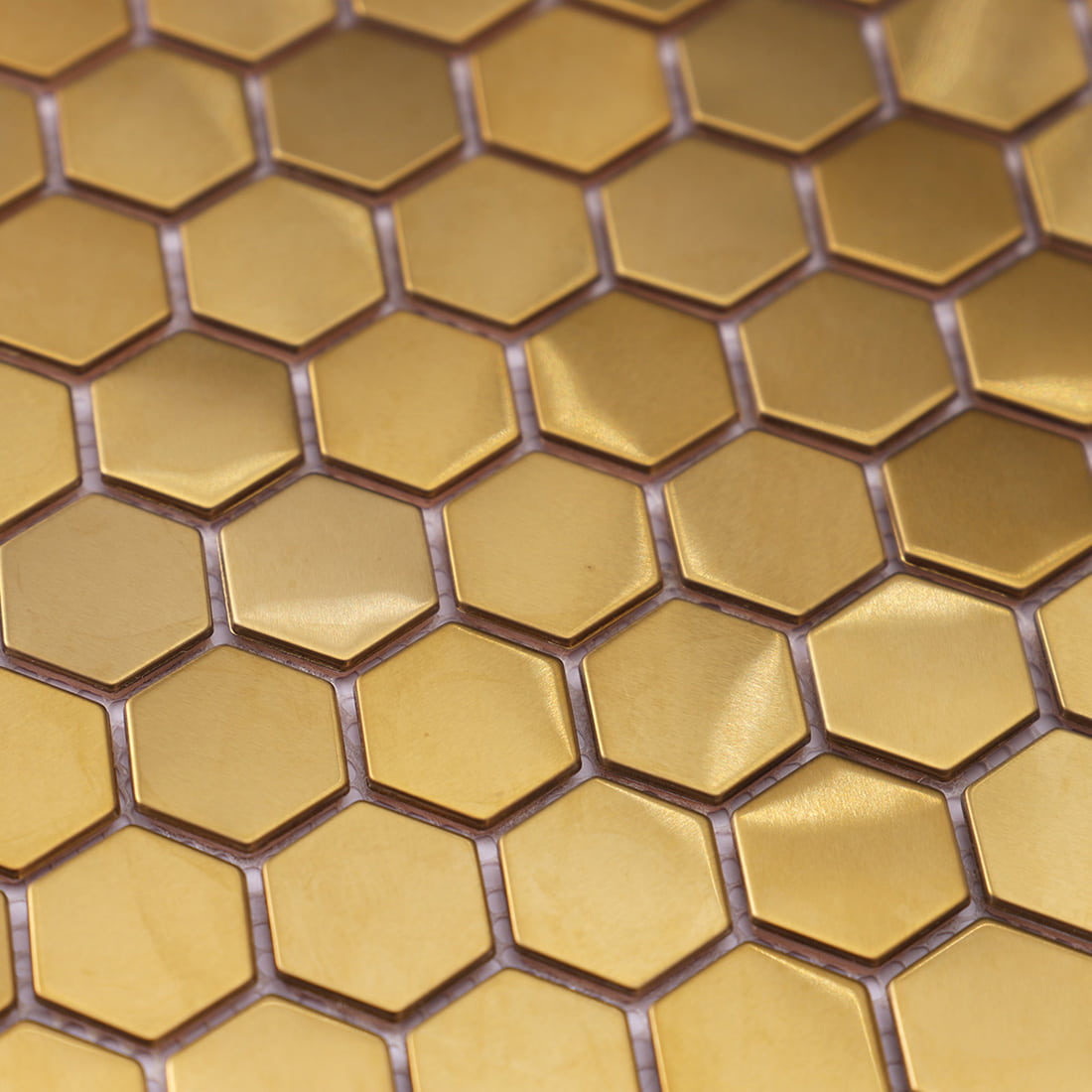 Macro detail showing the brushed finish and geometric shape of gold hexagon stainless steel tiles.