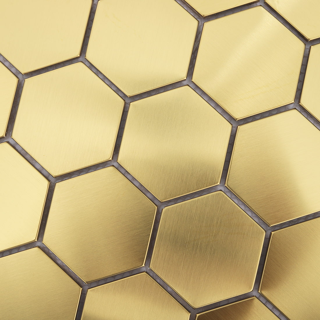 Macro detail showing the brushed finish and geometric shape of large gold hexagon tiles.