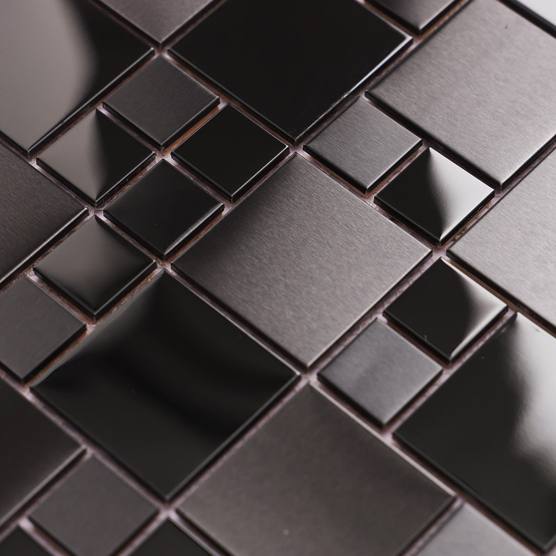 Macro view of reflective and brushed black metal mosaic tiles highlighting texture.