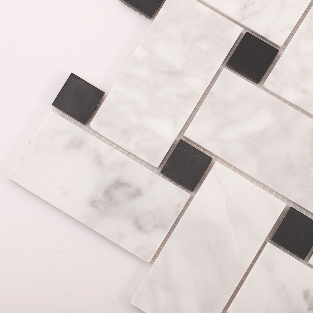 Angled close-up of marble mosaic with black square dots and grout lines.