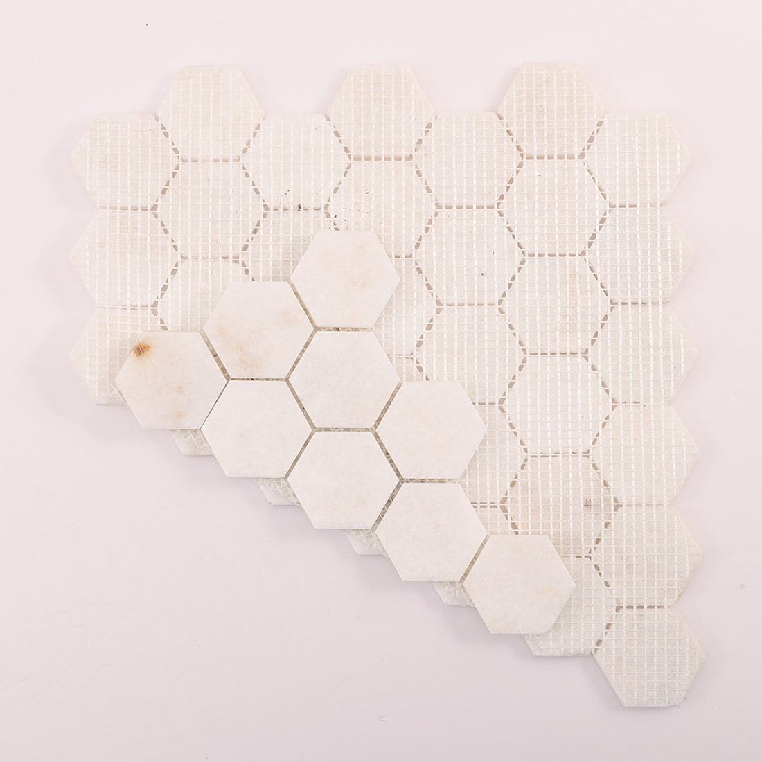 Back view of mesh-backed white marble hexagon mosaic sheet with sample pieces.