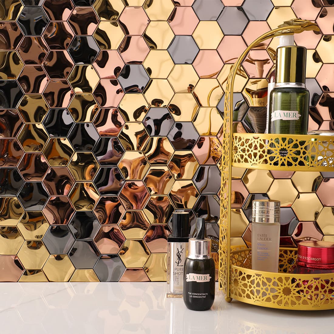 Mixed metal hexagon tiles used as a backsplash behind a gold cosmetic organizer.