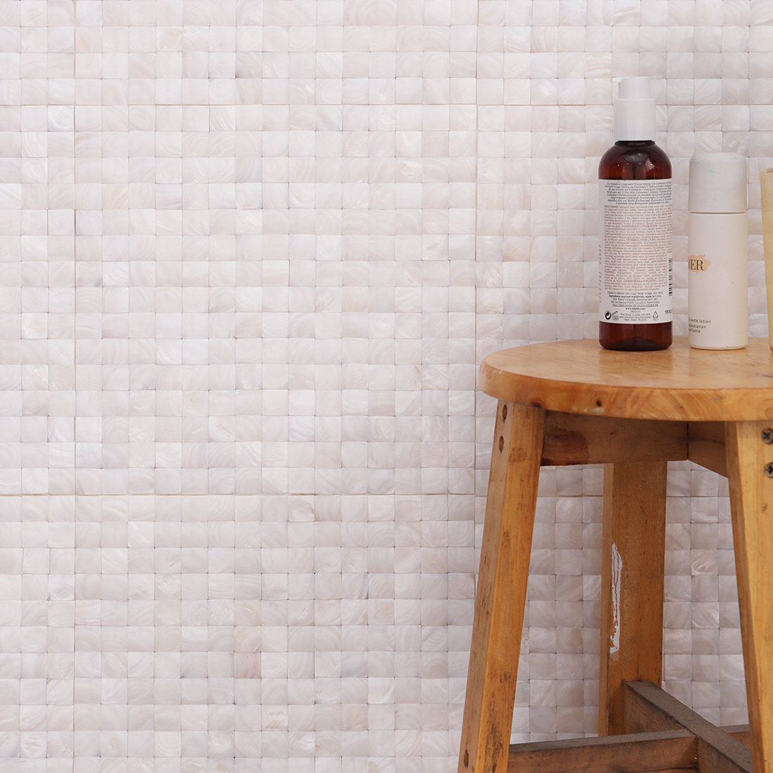 Installed mother of pearl mosaic wall with a wooden stool and bottles