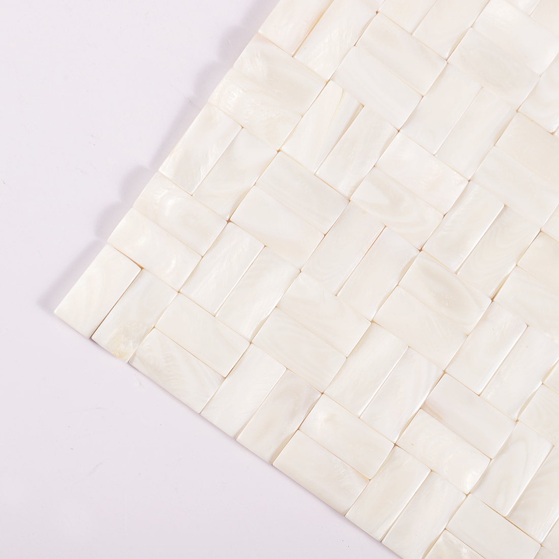 Corner view of mother of pearl basketweave mosaic tile sheet on light background