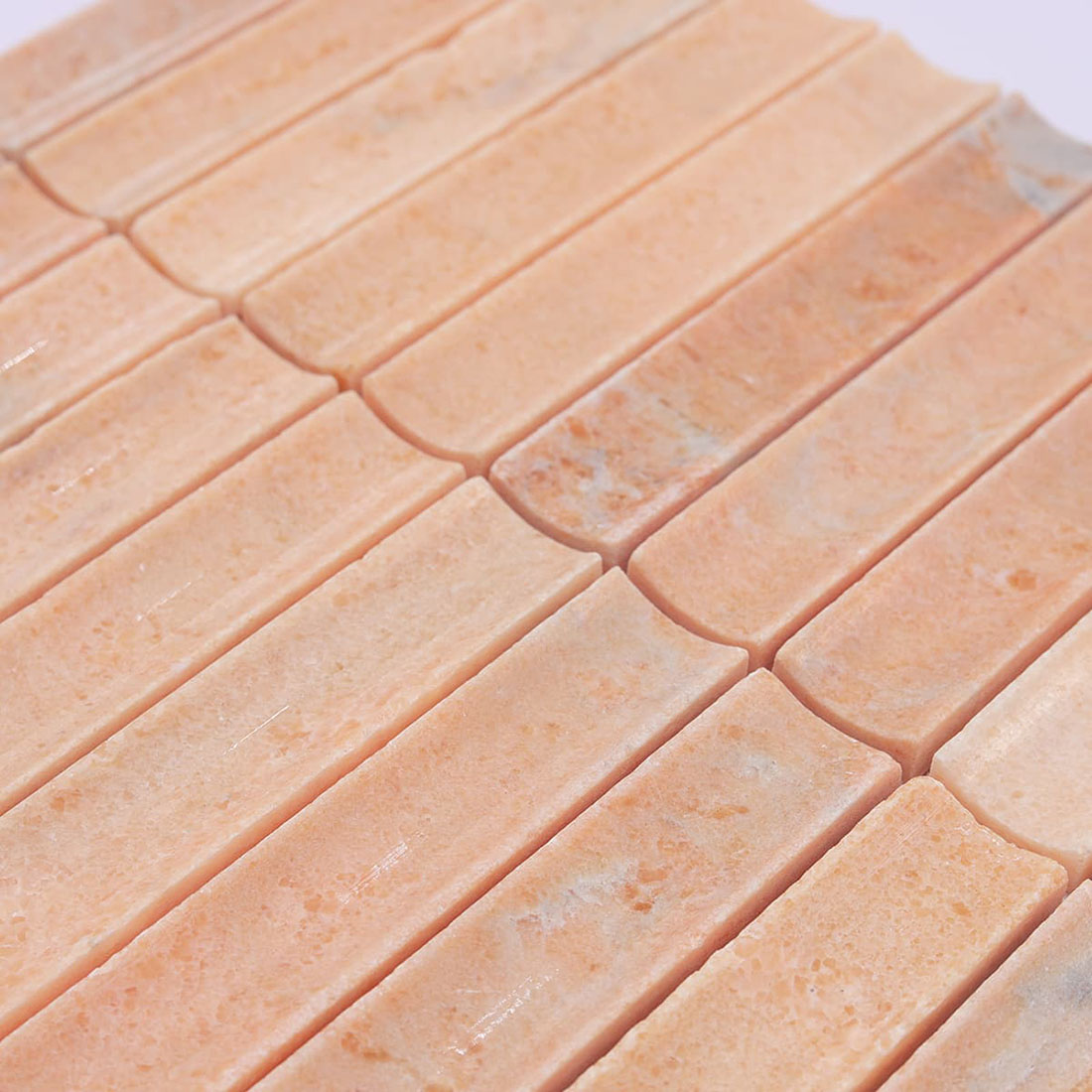 Angled view of peach stone mosaic showing the smooth concave strip surface