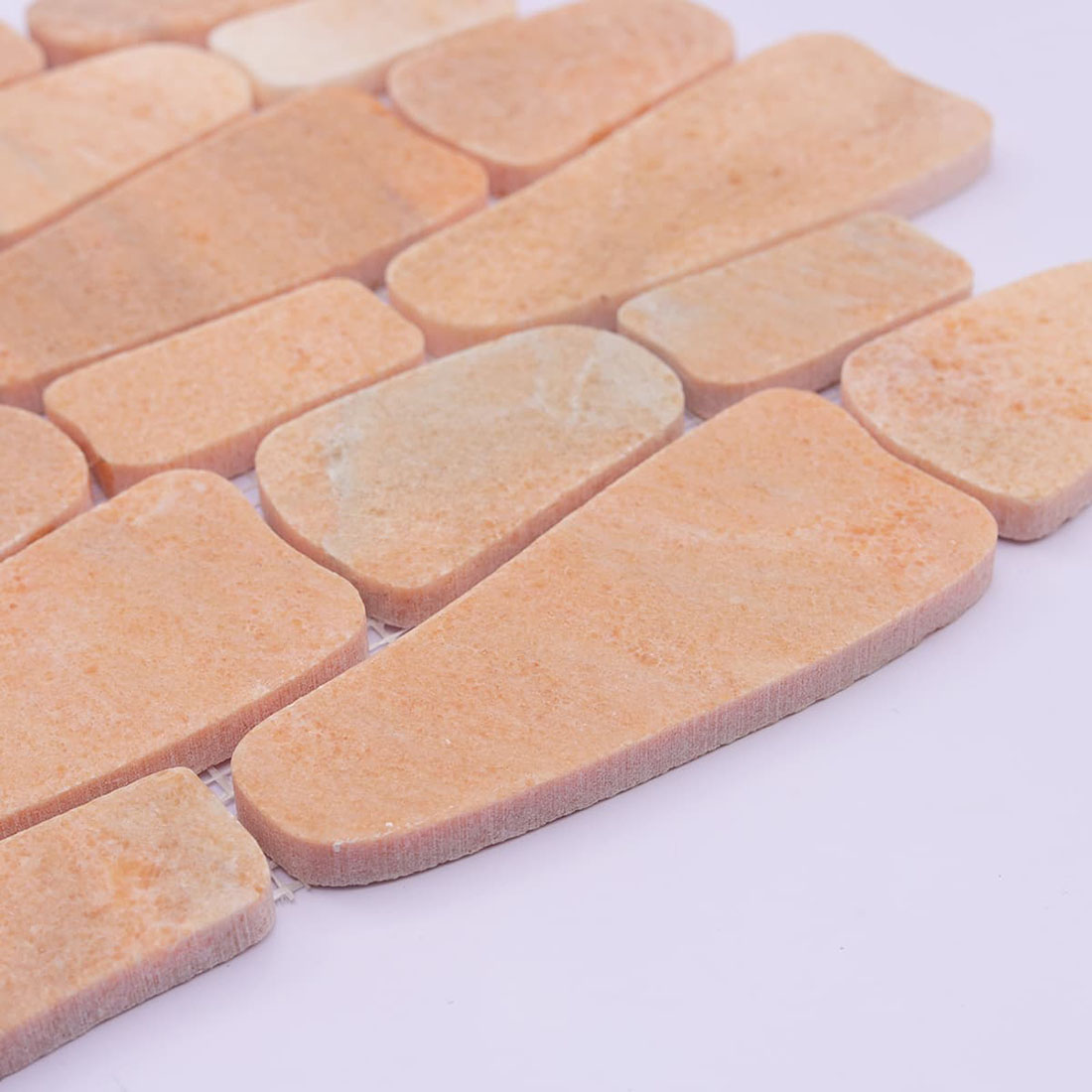 Angled view of peach stone mosaic showing tile thickness and matte finish