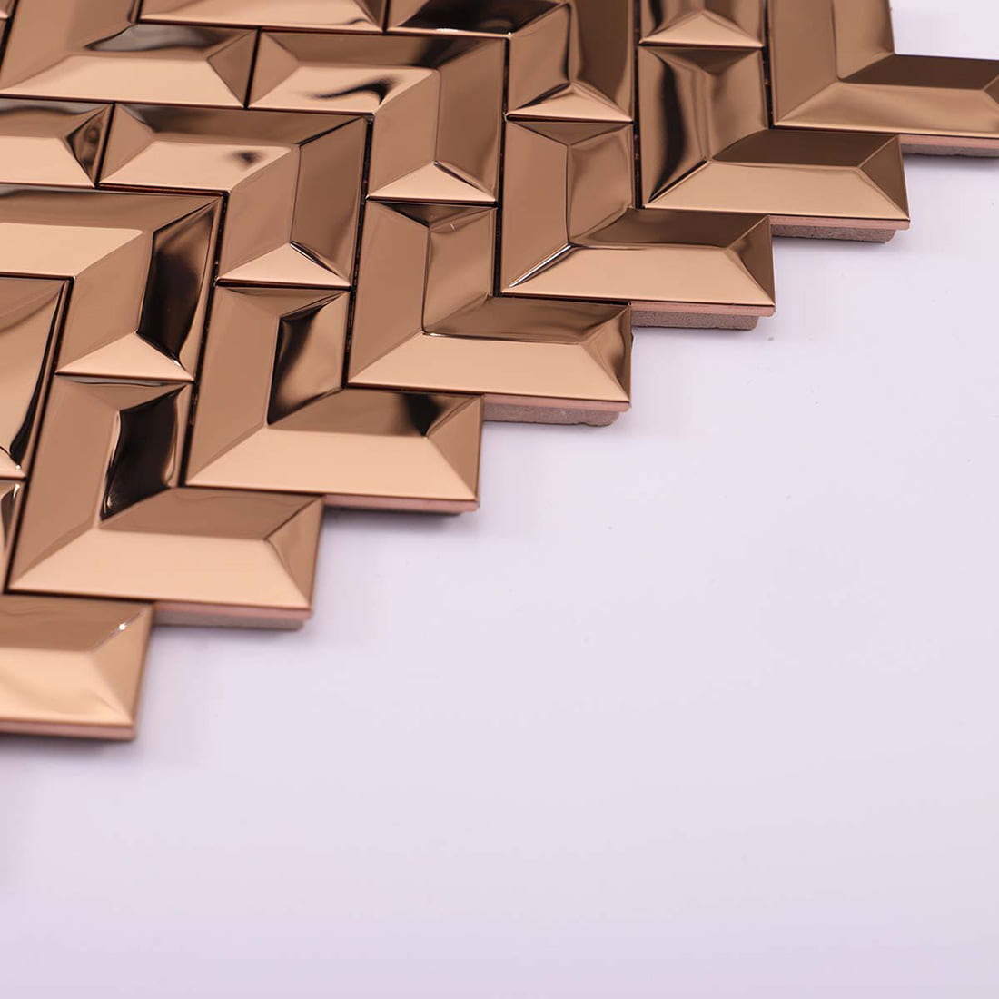 Perspective view showing the 3D beveled texture of rose gold chevron metal tiles.