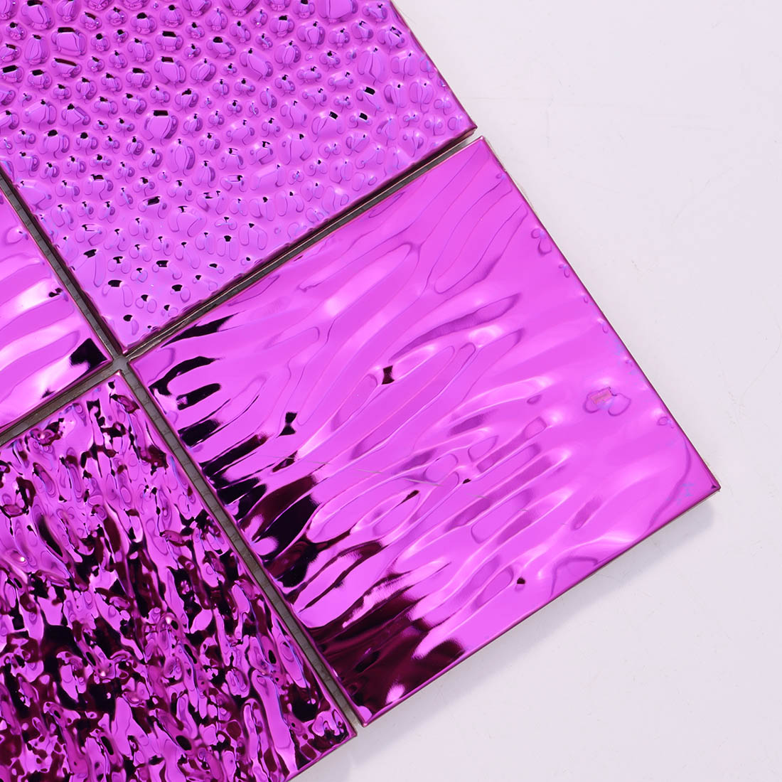 Close-up of pink stainless steel mosaic tiles with wavy and raised textures