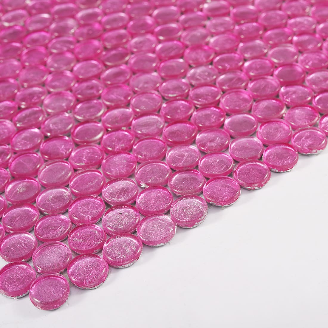 Angled view of pink round glass mosaic tile sheet showing depth and shine