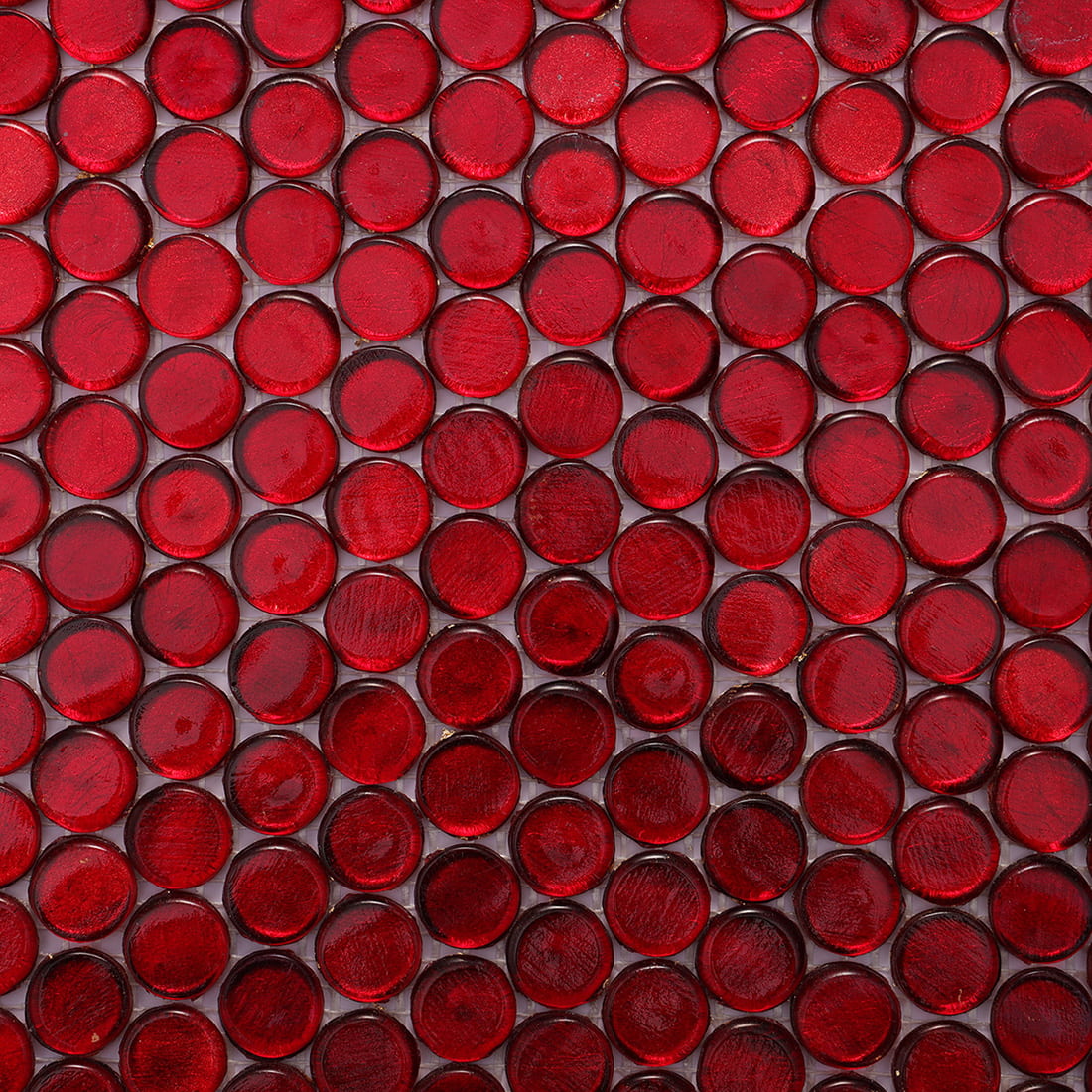 Angled close up of red foil penny round glass mosaic tiles showing depth