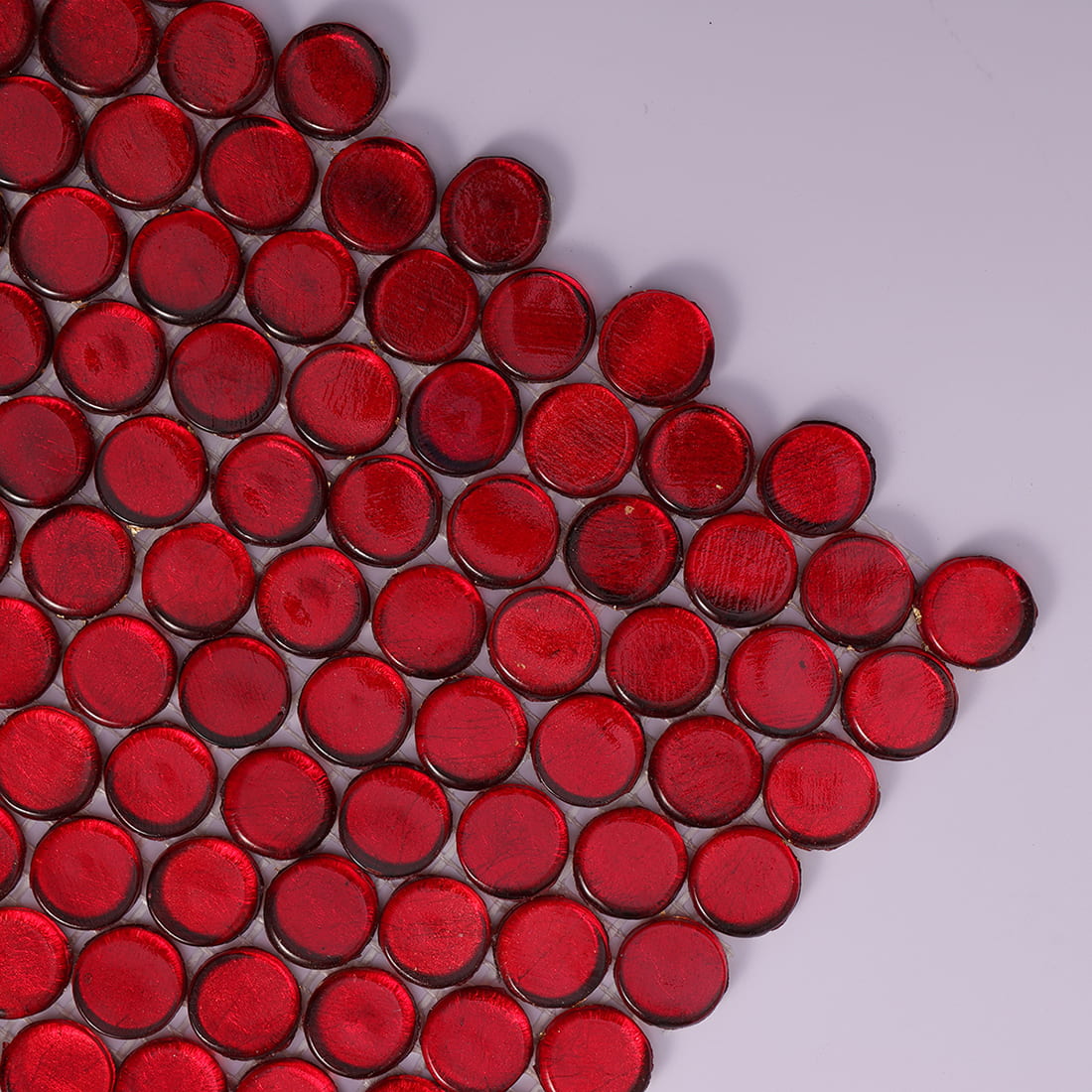 Corner close up of red foil penny round glass mosaic tiles