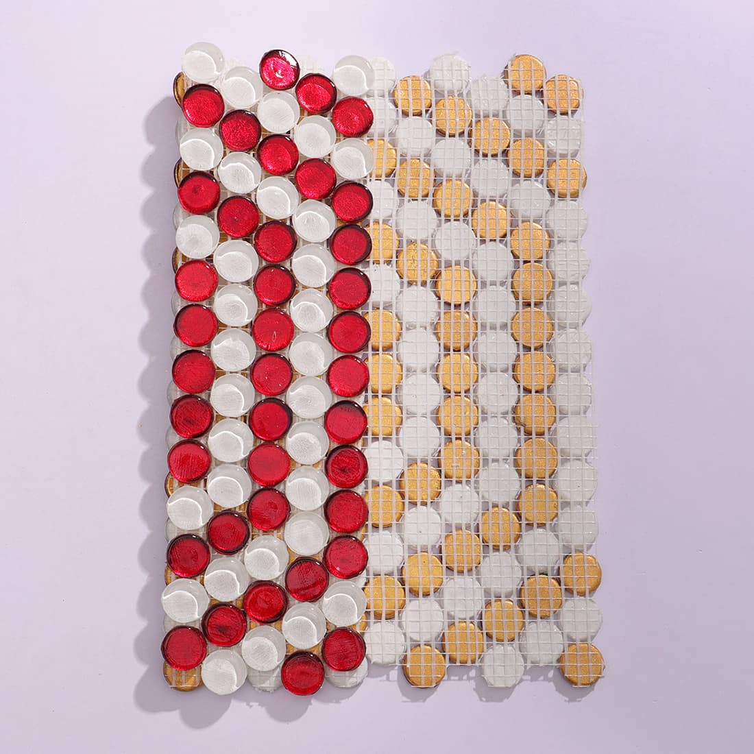 Backside view of red and white penny round glass mosaic tile with fiber mesh backing