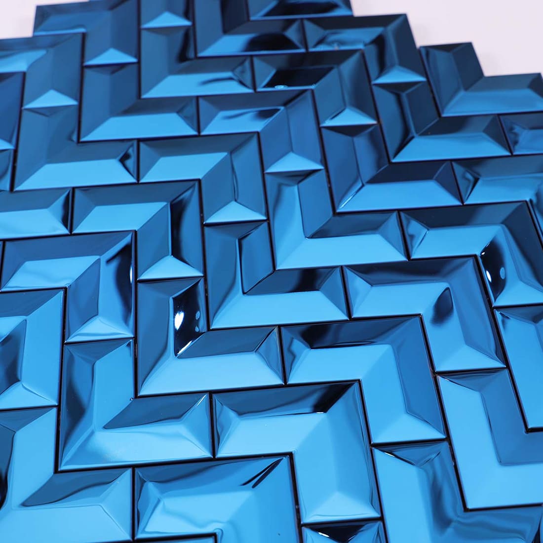 A close-up view capturing the reflective 3D surface of blue chevron wall tiles.