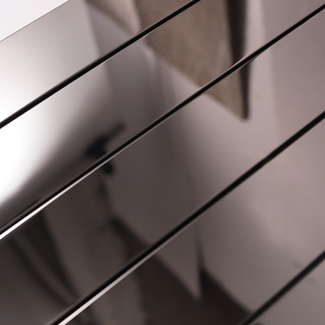 Macro detail of the reflective surface and seams on black glossy linear mosaic tiles.