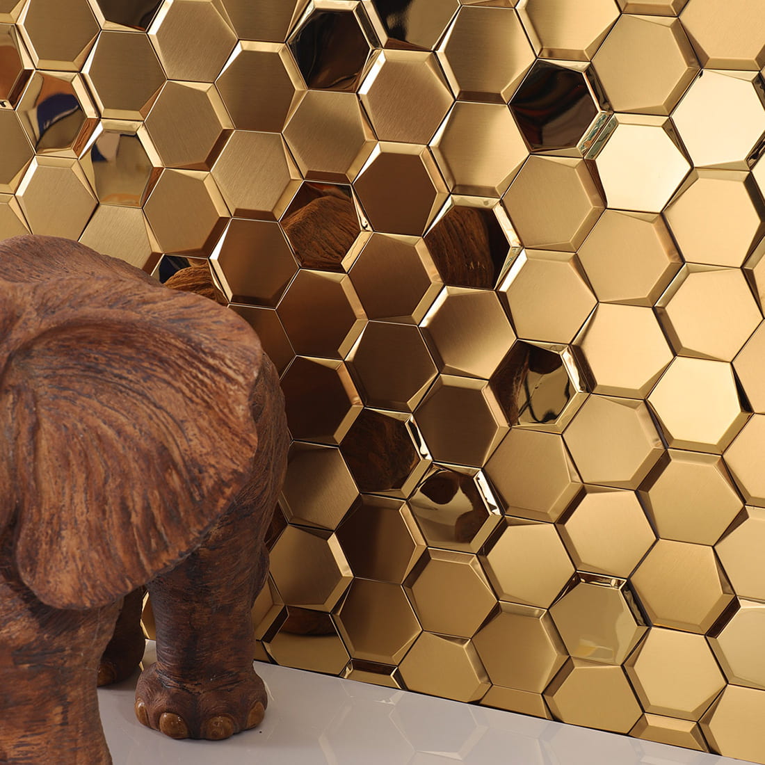 Angled view of a reflective gold hexagon tile wall showing light and shadows.