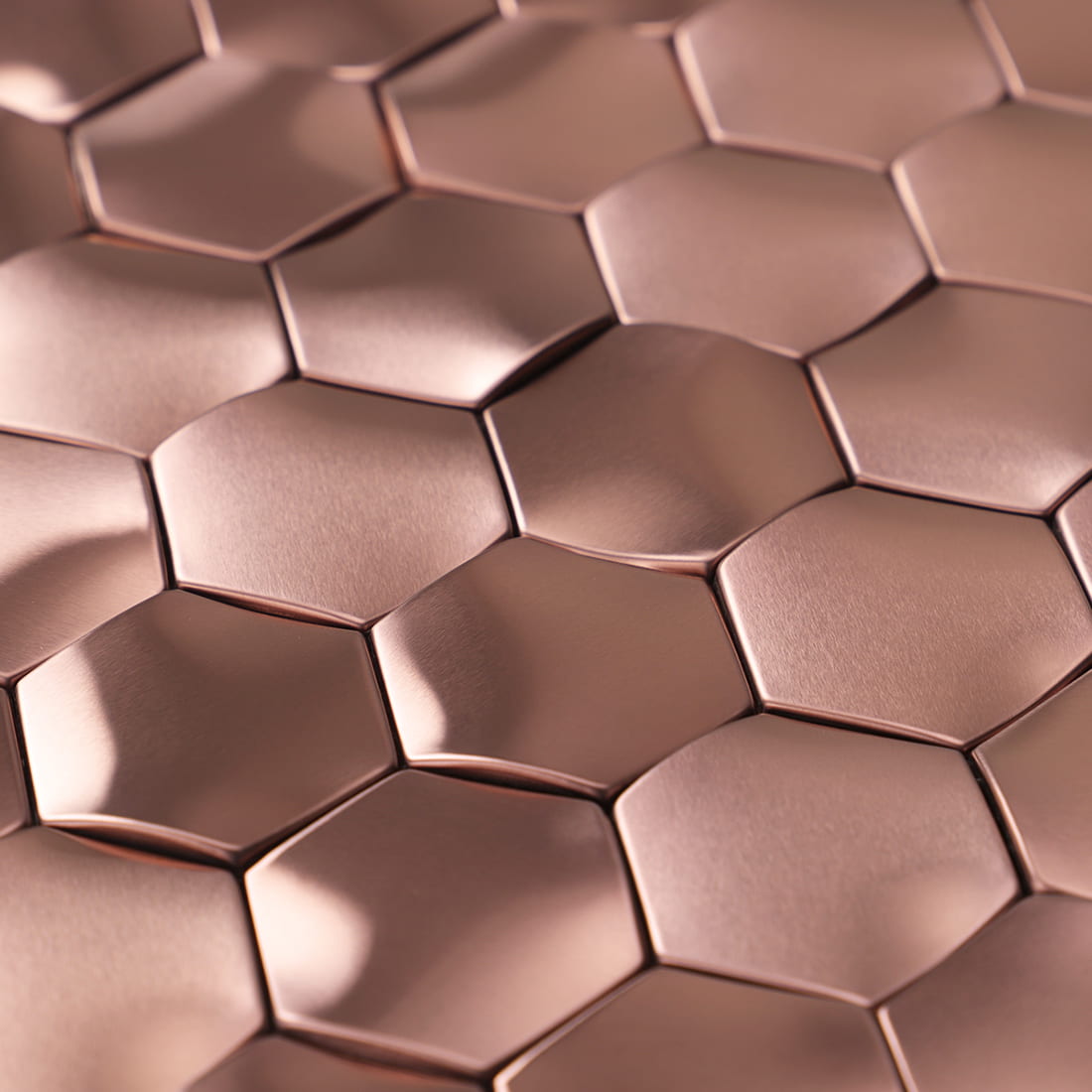 Tilted view showing the reflective brushed texture of 3D rose gold hexagon tiles.