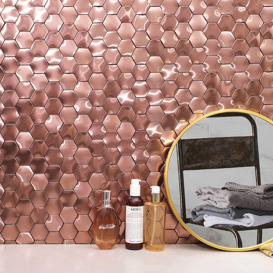 Bathroom interior with a rose gold 3D hexagon metal tile backsplash and mirror.