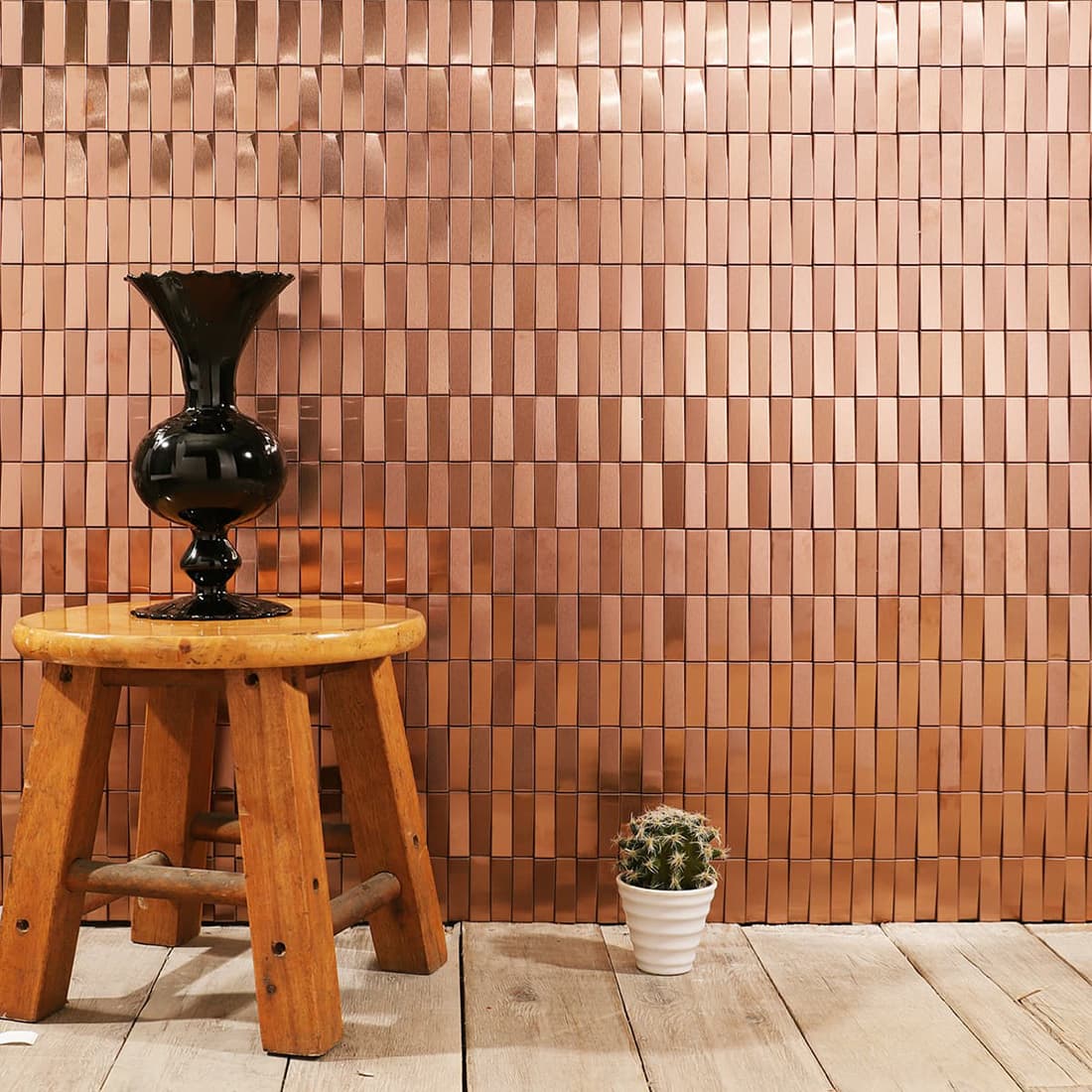 Luxury interior wall with rose gold 3D rectangular tiles, a vase, and a cactus.