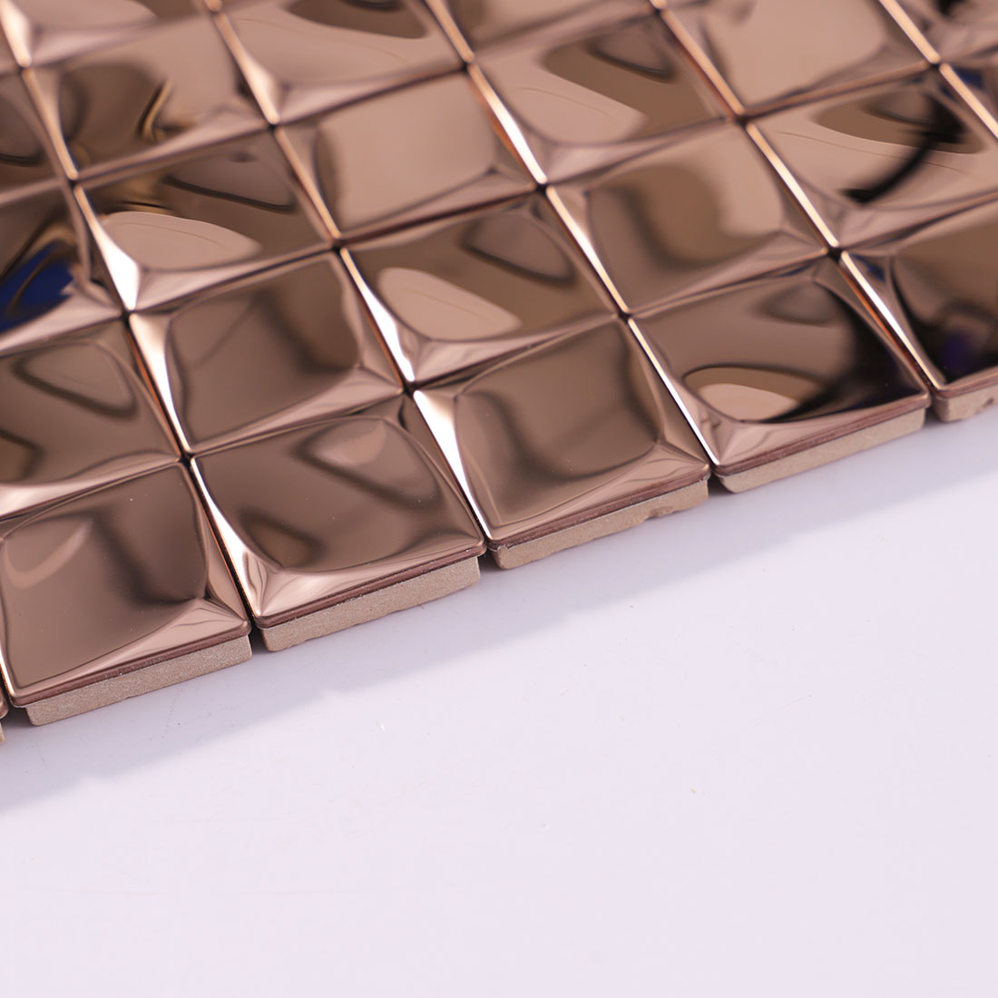 Angled view of rose gold 3D square metal mosaic tile sheet edge