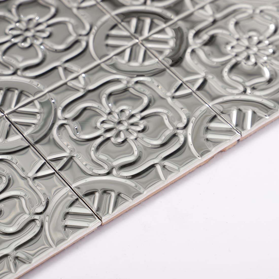 Side view of silver floral mosaic tile showing edge and backing