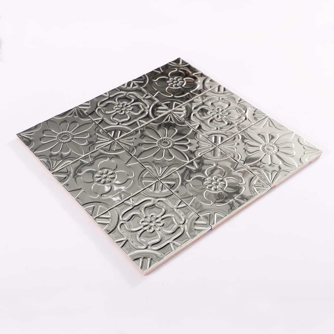 Diagonal view of shiny silver floral embossed mosaic tile sheet