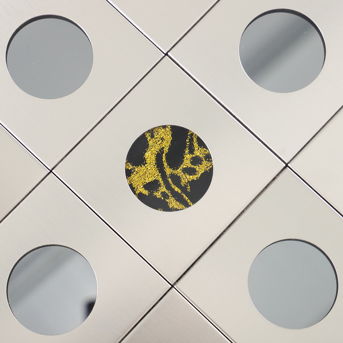 Close view of round glass inlay on silver brushed metal mosaic tile