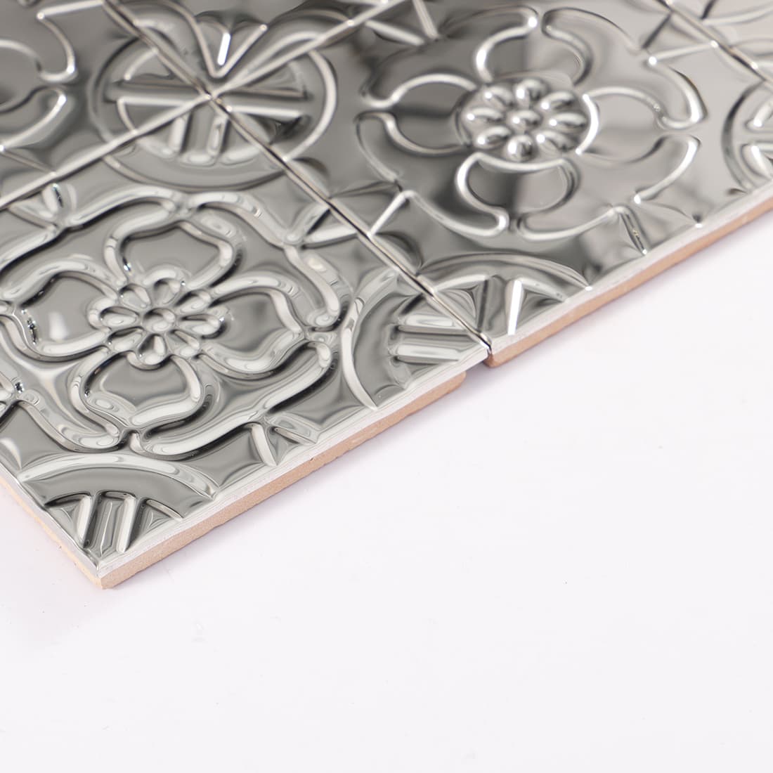Side view of silver embossed tile showing ceramic base thickness