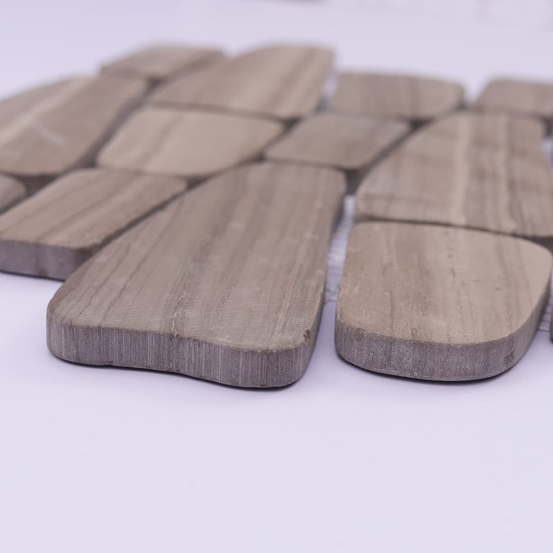 Angled view of taupe pebble stone mosaic showing thickness and rounded edges