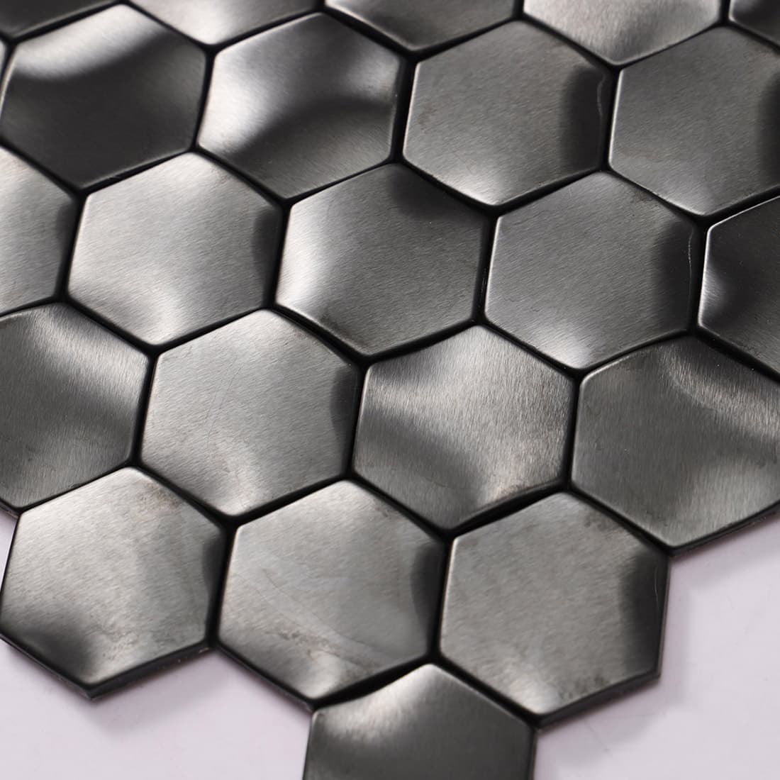 Detailed texture of a brushed black metal hexagon mosaic tile surface.