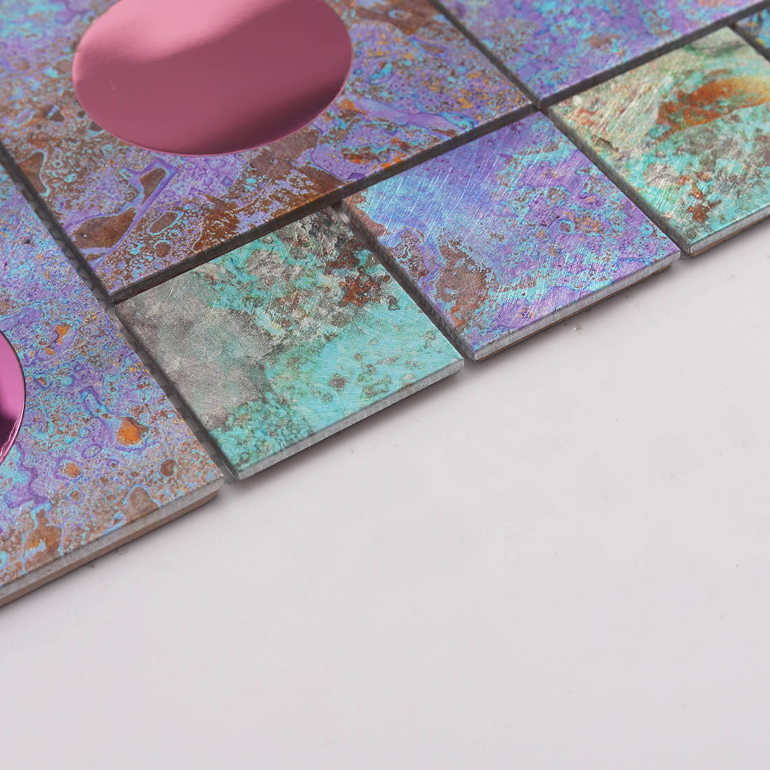 Edge detail of textured iridescent aluminum mosaic tile with pink mirror glass