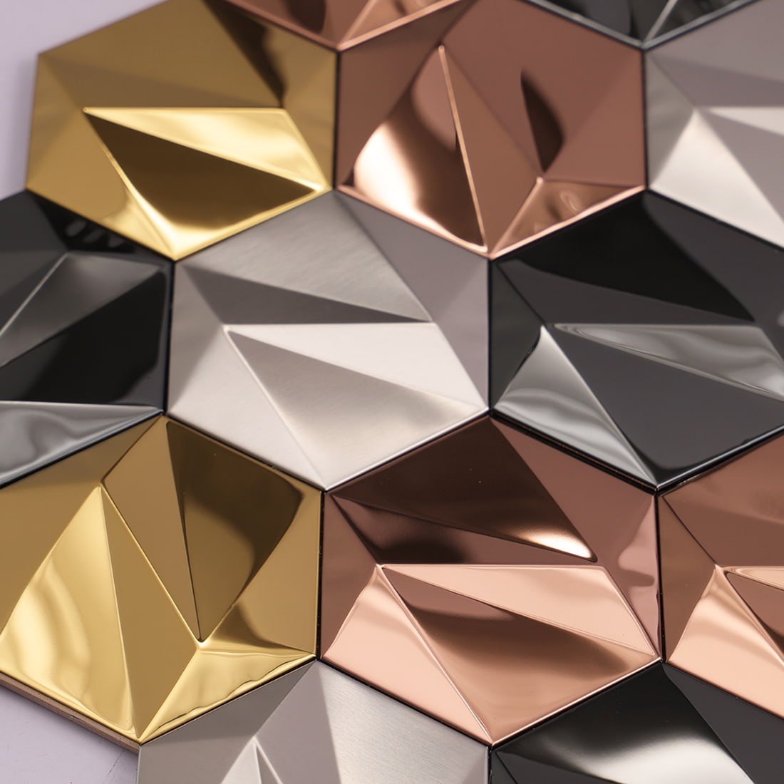 Detail shot of textured and polished metal hexagon tiles in rose gold and silver.
