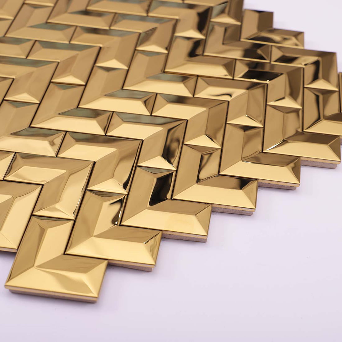 A tilted view of a gold chevron stainless steel mosaic tile sheet.