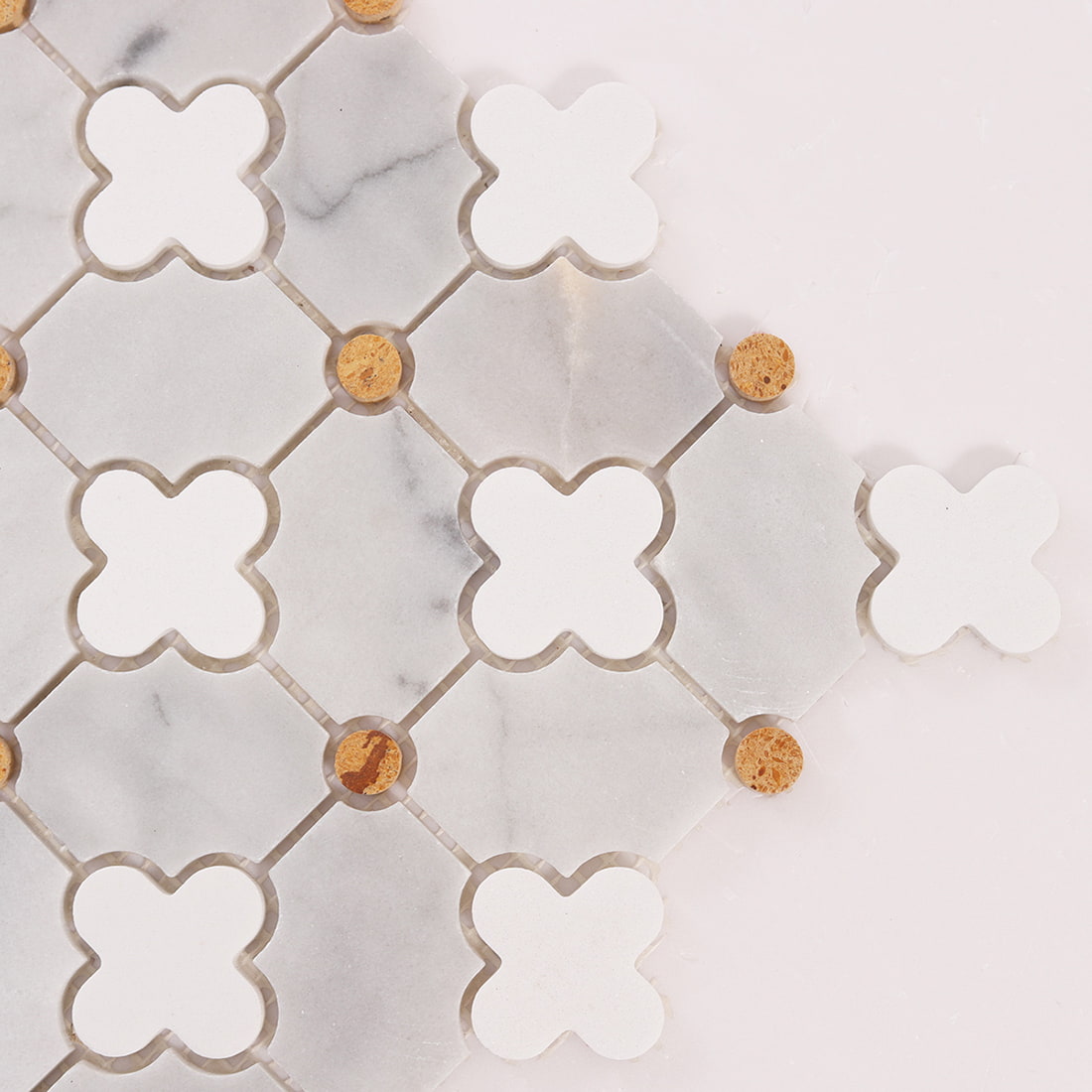 Close up corner of clover mosaic showing edge cuts, grout spacing, and gold dots