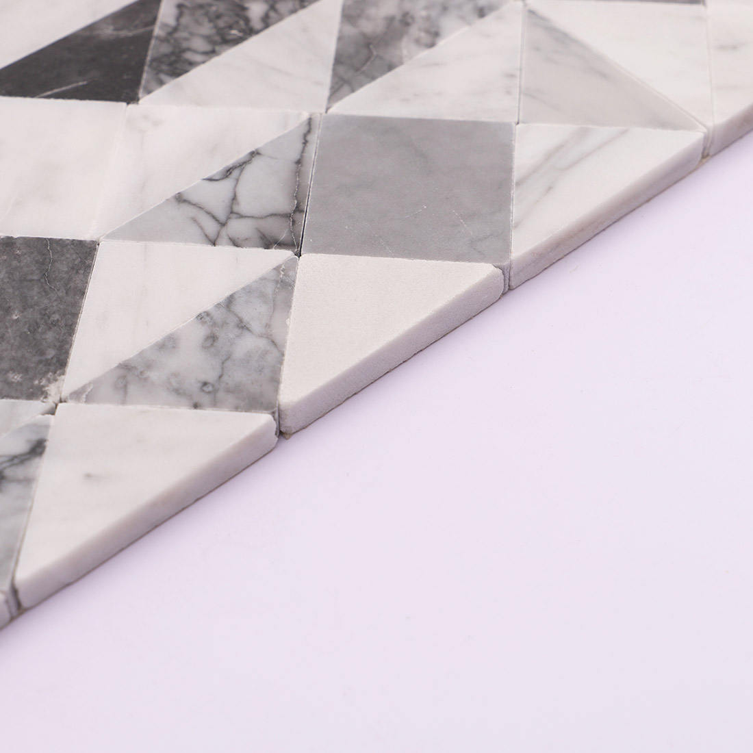Side edge of white gray geometric marble mosaic tile showing natural stone thickness