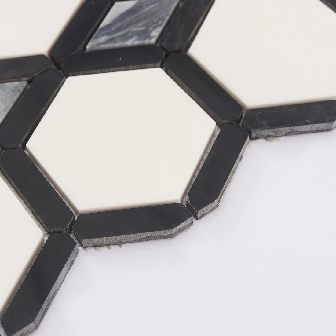 Edge view of white hexagon marble tile framed by black stone strips