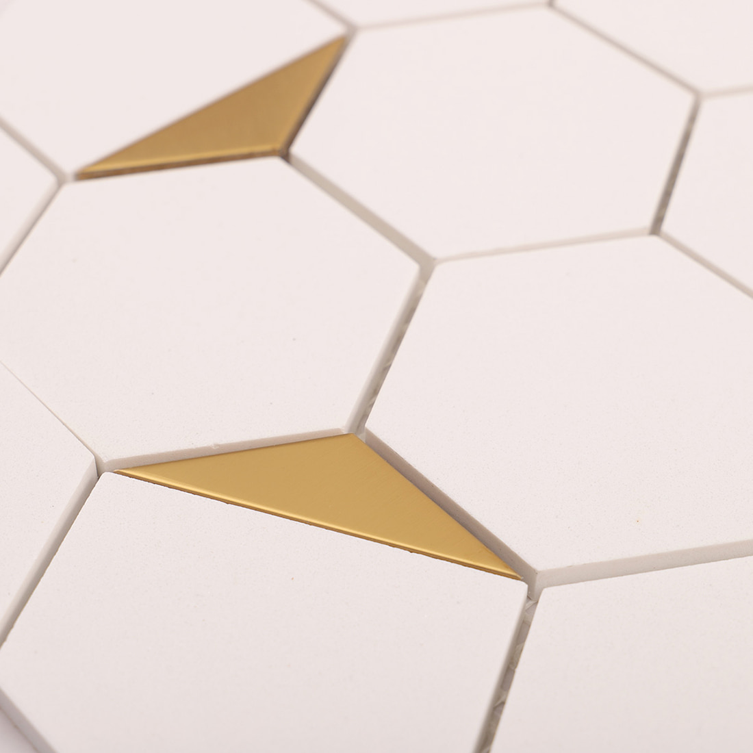 Macro view of white hexagon tiles with multiple gold triangle accents
