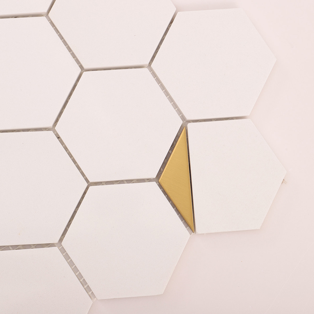 Close-up of gold triangle insert between white hexagon tiles