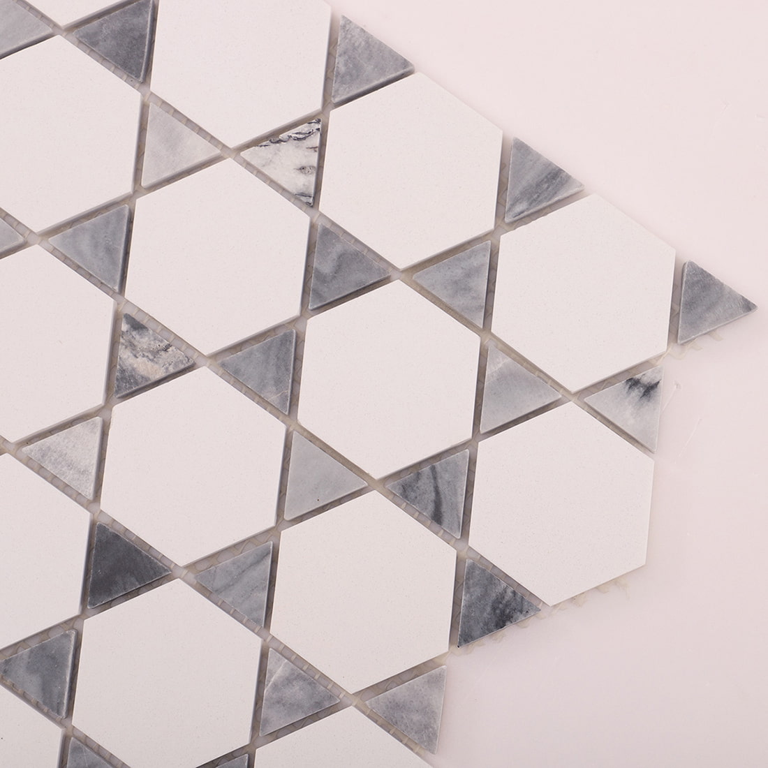 Corner close up of white hexagon marble mosaic showing triangle accents and grout spacing