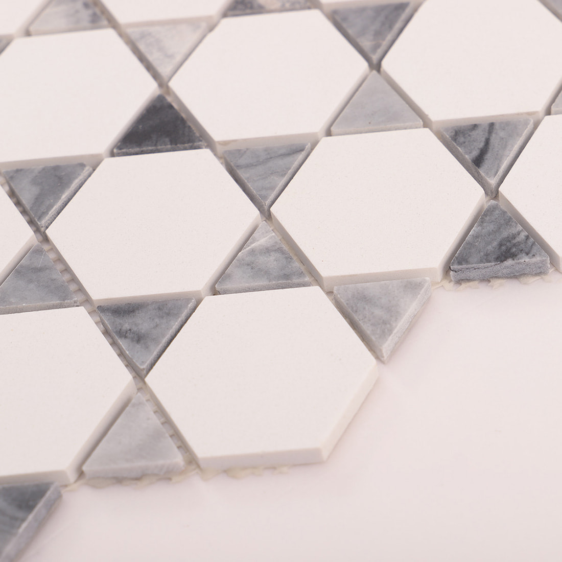 Macro pattern detail of white hexagon marble mosaic with triangle inserts and joints