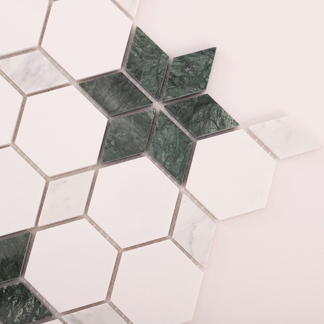 Angled corner view of white hexagon mosaic with green star inlay detail.
