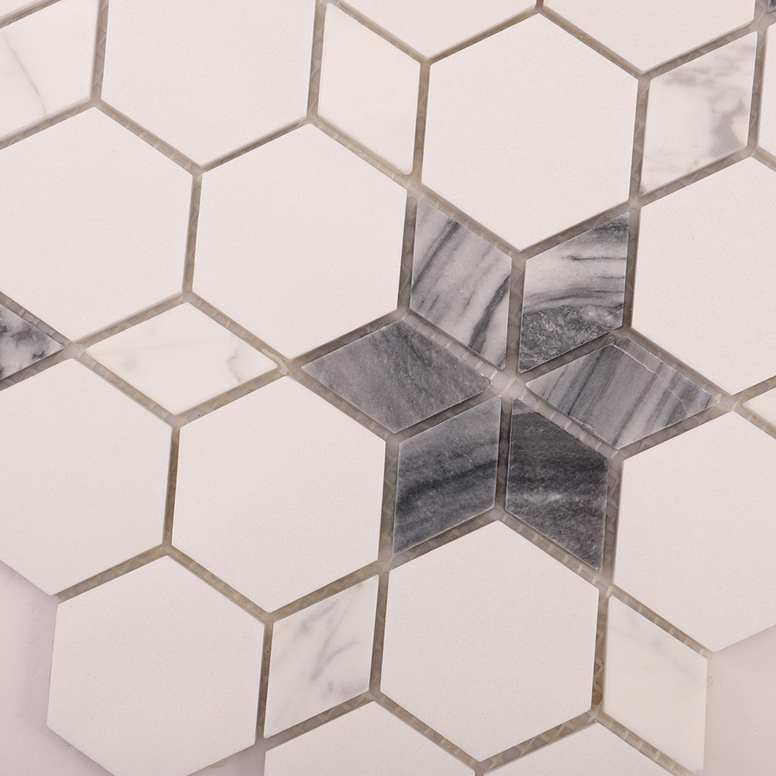 Close-up of grey marble star inlay surrounded by white hexagon tiles.