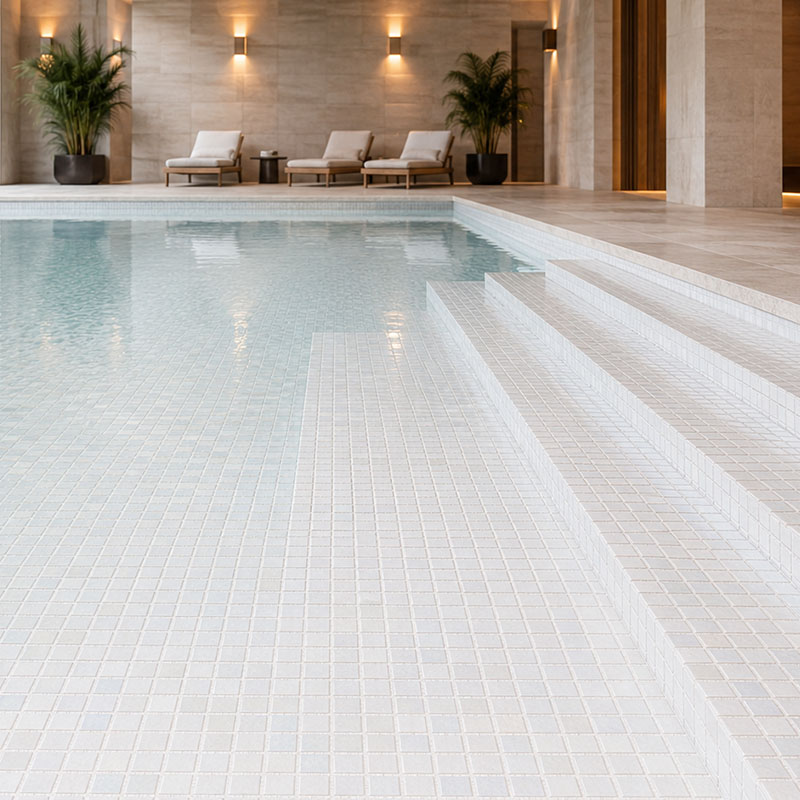 White iridescent pool mosaic tiles covering a luxury indoor pool floor and steps
