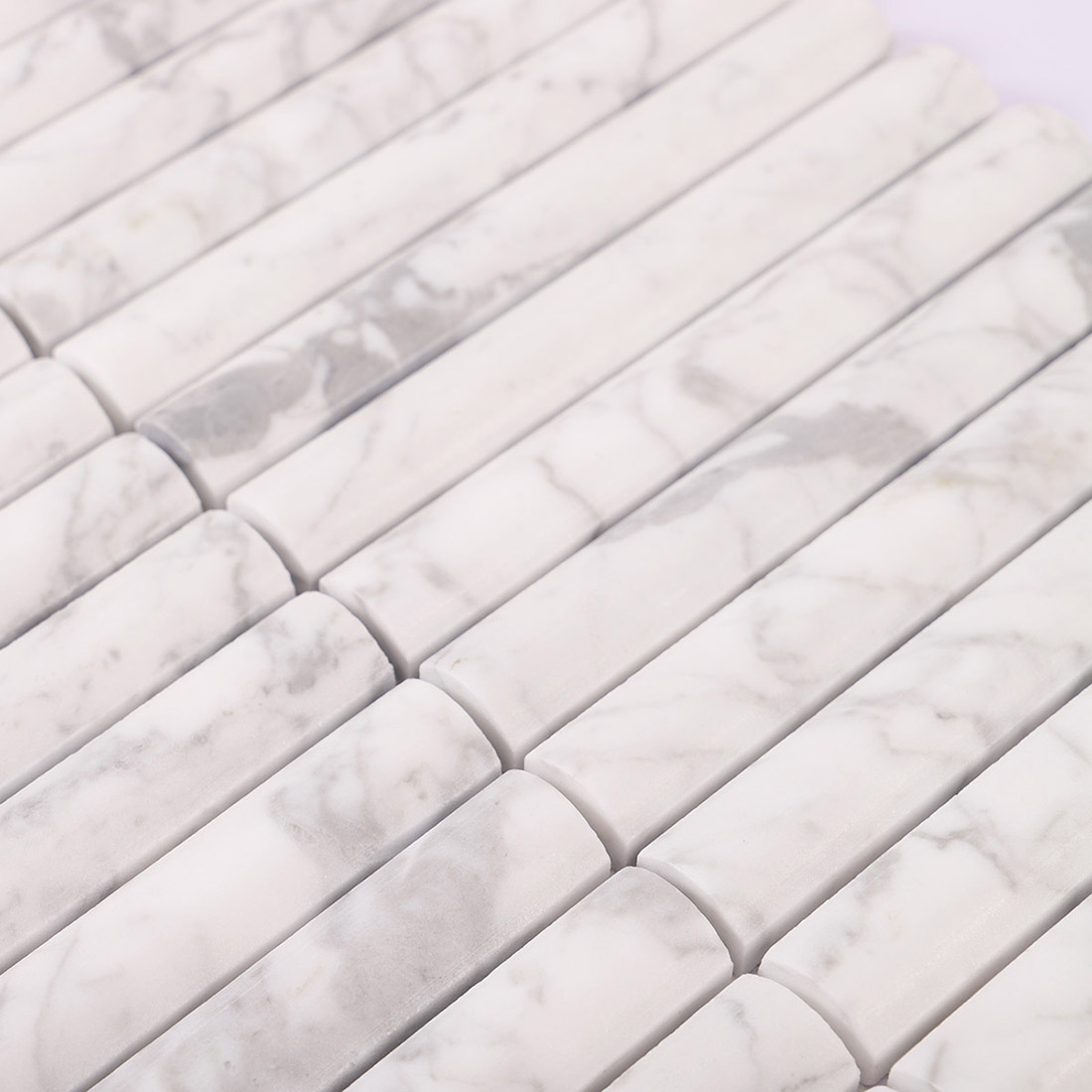 Raised white marble half round strips with smooth curved surfaces and gray veins